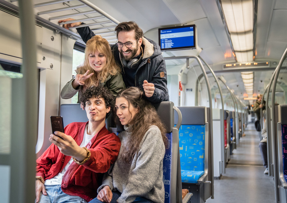 Vier Freunde nehmen ein Selfie auf den Sitzplätzen der S-Bahn auf