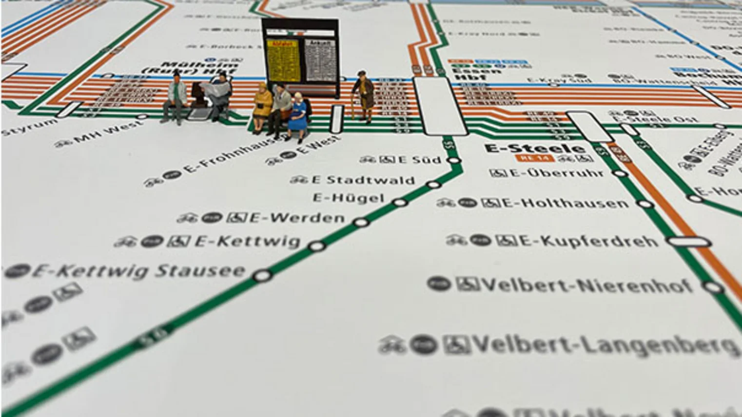 Modellfiguren sitzen auf dem VRR-Schienenschnellverkehrsplan 