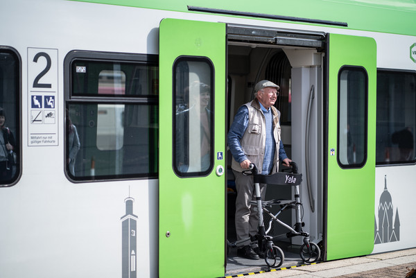 Ein älterer Mann steigt mit seinem Rollator aus der S-Bahn aus