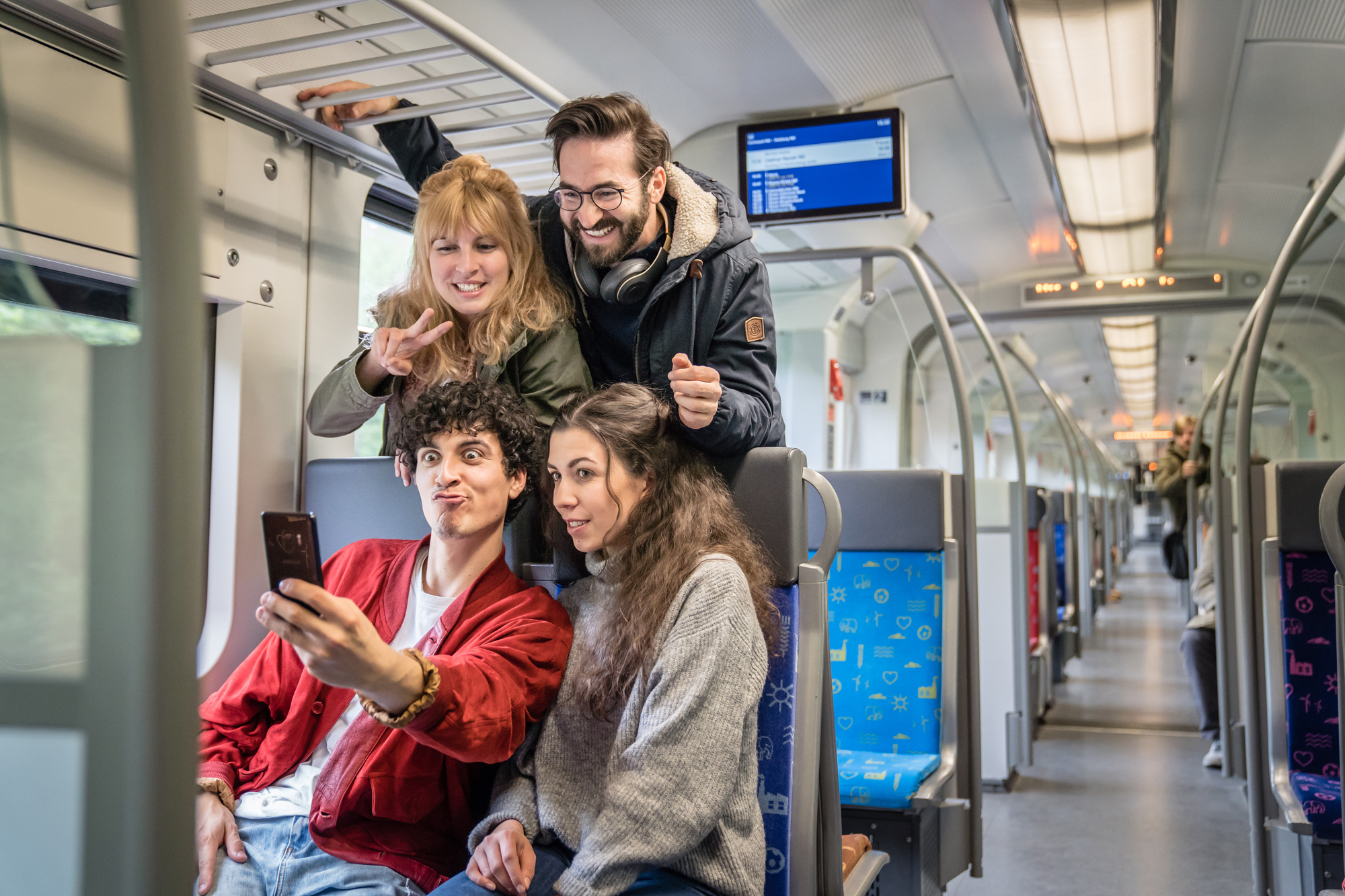 Vier Freunde nehmen ein Selfie auf den Sitzplätzen der S-Bahn auf