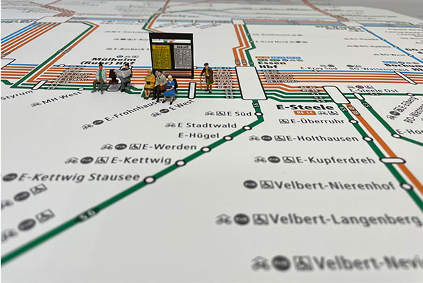 Modellfiguren sitzen auf dem VRR-Schienenschnellverkehrsplan 